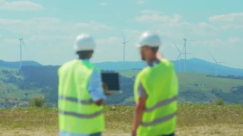 Ein Team von Ingenieuren und Technikern überprüft Informationen zu Windturbinen mithilfe digitaler Geräte in