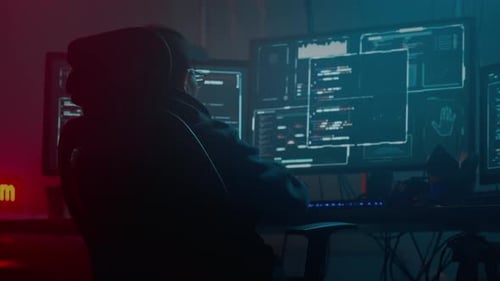 Hooded Hacker Working at Computer Station