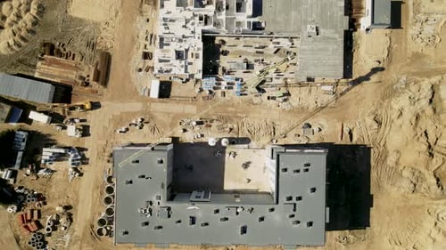 Aerial top down: Sandy construction site build high housing blocks during sunny day.