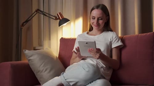 Woman Relaxing Using Tablet on Sofa at Home