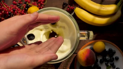 Top View Child's Hands Throw a Handful of Ripe Blueberries Into a Blender Mixing a Cocktail of Milk