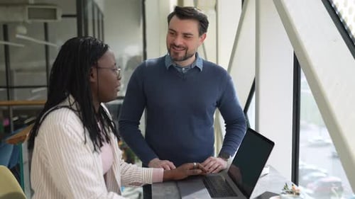 Multinational colleagues working together using a laptop in a modern coworking space