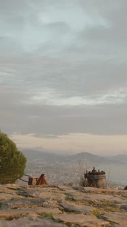 Vertical video. A rocky path descends from the mountain with railings leading to the city.