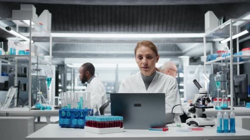 Scientists Working in Modern Laboratory with Laptop and Equipment