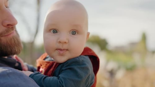 Loving Father Holds Cute Baby Outdoors in Daylight