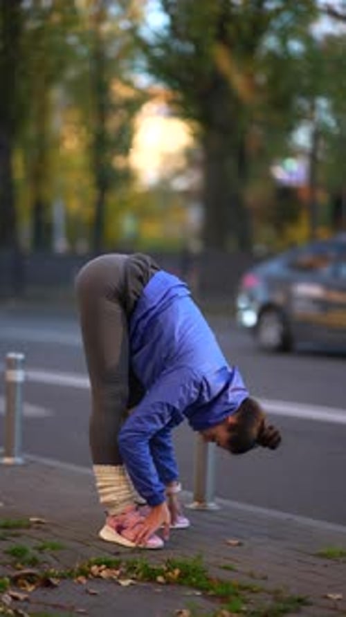 Young Female Athlete in Sportswear Doing Warm Up Exercises on City Street