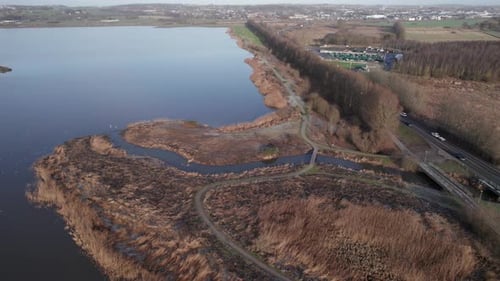 Vista desde un Zumbido de una carretera con coches que circulan junto a un lago: se inclina hacia arriba y Dolly en la foto