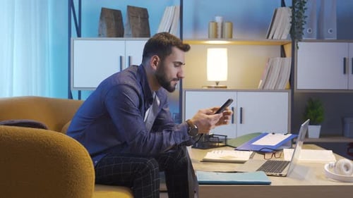 Young Adult Man Uses Smartphone on Couch