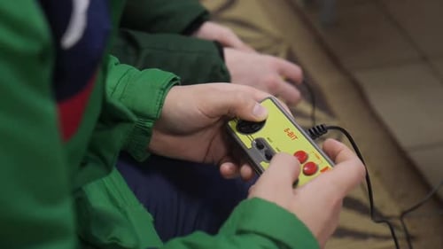 People in Jackets Play Eight Bit Set Top Box in Light Room