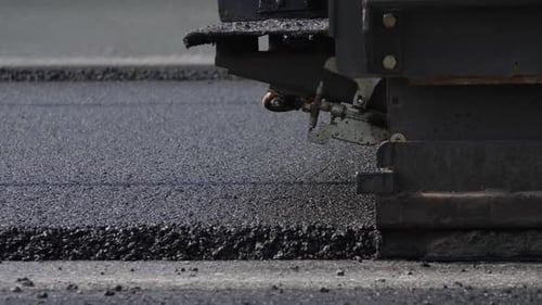 Asphaltschicht auf der Fahrbahn verteilt und vom Straßenfertiger mit Estrich versehen
