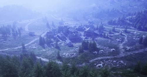 Matin brumeux sur un village isolé entouré d'arbres et de collines luxuriants