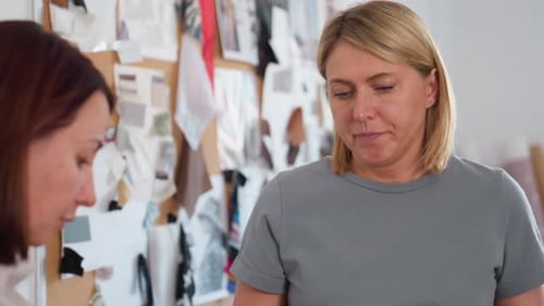Elegante Frauen arbeiten zusammen, eine zeichnet, während die andere Daumen hoch gibt