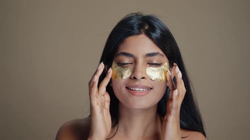 Woman Applies Gold Eye Patches for Beauty Treatment