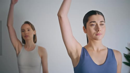 Two Young Women Stretch Necks Indoors