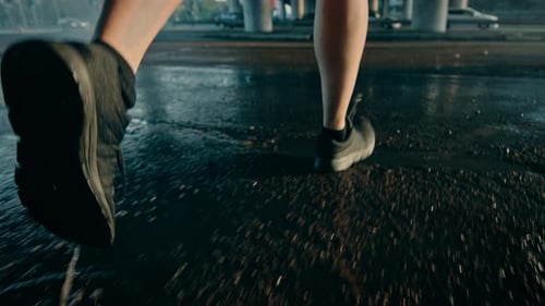 Close Up Leg Shot of an Athletic Young Man in Sports Outfit Jogging in a Rainy Street. He is Runnin