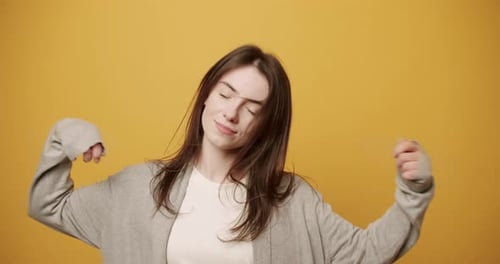 Cheerful Woman Dancing Energetically on Yellow Background