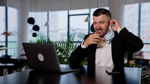Man in Suit Putting On Surgical Mask in Office