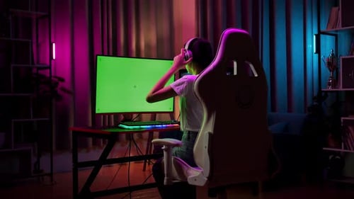 Teen Girl Gamer Wearing Head Phones And Start Play Video Game On Computer With Mock Up Green Screen