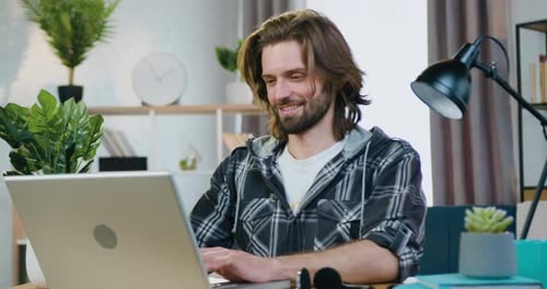 Close up of smiling man using laptop in beautifully decorated room and working with start up project