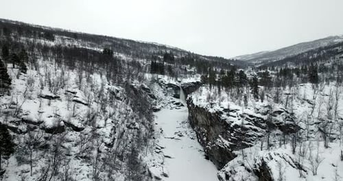 Luftaufnahme über verschneiter Winterwildnis - gefrorener Fluss und Wasserfälle in der Schlucht