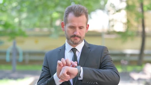 Businessman Using Smartwatch Outdoors in Urban Setting