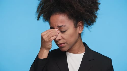 Stressed Woman Rubbing Face on Blue Background