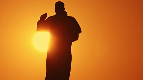 Couple Silhouetted Kissing and Dancing at Sunset