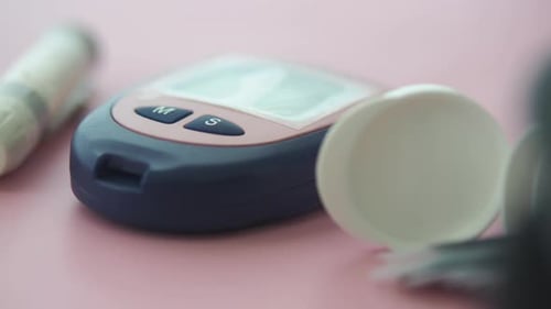 Blood Glucose Monitor and Supplies on a Pink Background