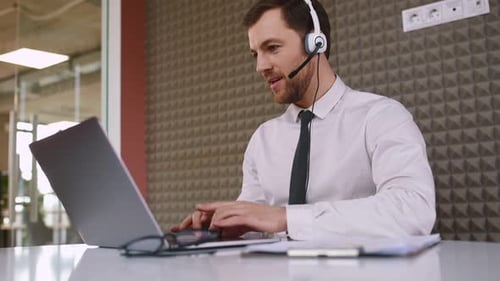 Office worker is sitting by a laptop and having online conference. Talking, giving advice