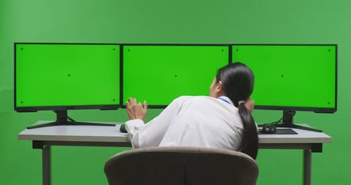 Asian Woman Boring While Working With Mock Up Multiple Computer Monitor In Green Screen Studio