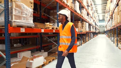 Logistics Operator Walking Through Warehouse Aisles