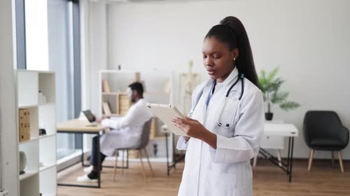 Healthcare Professional Reviewing Patient Data on a Tablet in Modern Office