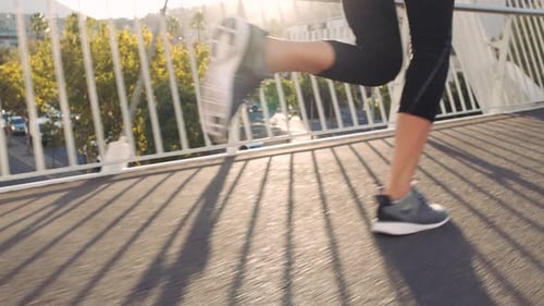 Fit woman running and jogging on a bridge in the city outdoors