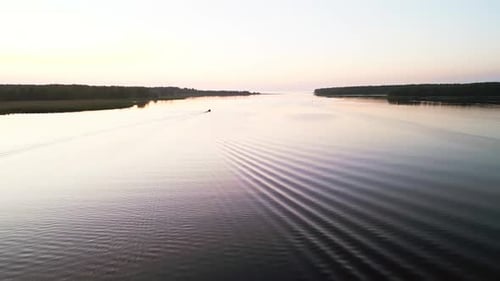 Serene Sunrise View of a River with a Distant Boat Gliding Peacefully Creating a Tranquil and