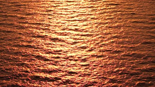 Luftaufnahme der Meereswasseroberfläche auf goldenem Meerwasser bei Sonnenuntergang, Sonnenblendung, abstrakter nautischer Sommerozean
