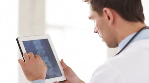 Doctor examines x-ray image on tablet in hospital