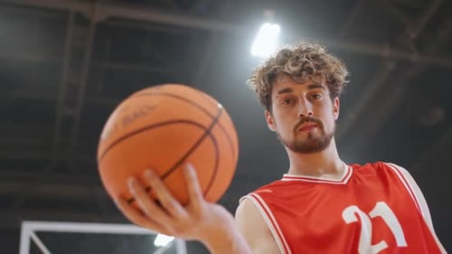 Porträt eines kaukasischen Basketballspielers, der ernsthaft in die Kamera blickt und den Ball in der Hand hält