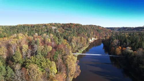 Aerial view of a serene autumn river surrounded by colorful foliage