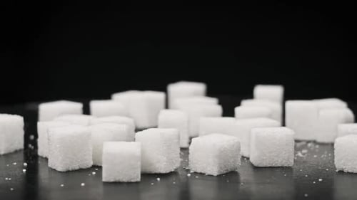Sugar Cubes Rotate on the Table CloseUp on Black Background