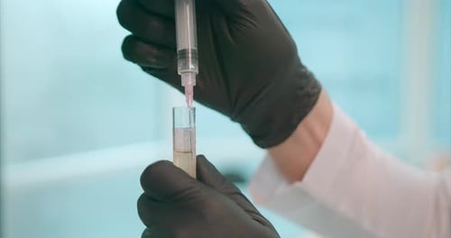 Extreme close-up of an unrecognizable doctor wearing latex gloves taking syringe with vaccine from a