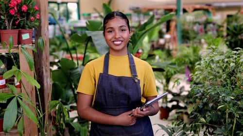 Confident young african american woman working in a flower shop holding a digital tablet. Successful