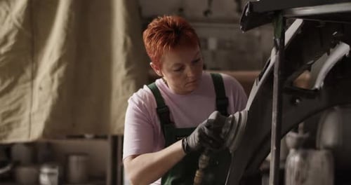 Woman Sanding Auto Body in Workshop
