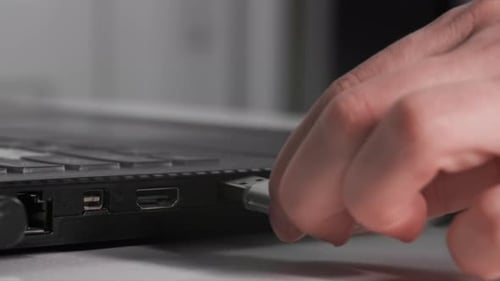Female Hand Inserts USB Flash Drive Into Laptop to Transfer Information Closeup