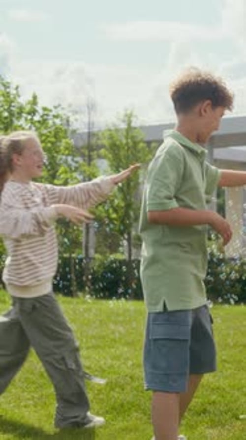 Happy Boys Jumping and Walking around Girls with Toy Gun Blowing Soap Bubbles
