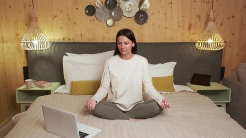 Woman Meditating on Bed with Laptop