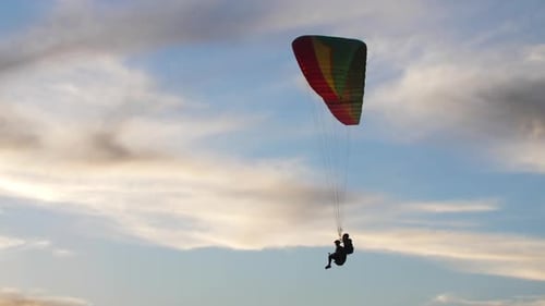 Gleitschirm fliegt zusammen mit Passagier am blauen Himmel bei Sonnenuntergang