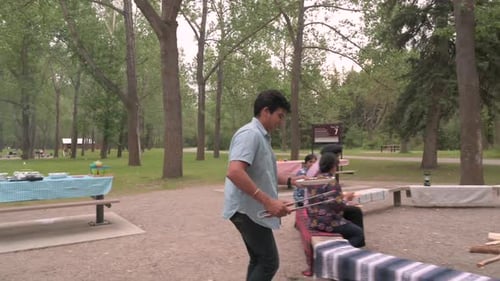 Indian Man Barbecuing Food At Family Picnic In Park