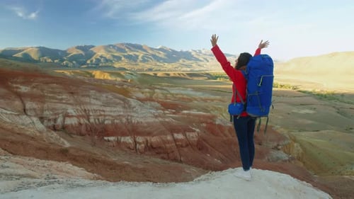 Woman Hiker Wih Big Backpack Enjoying View of Mountain Summit with Raising Her Arms Up Into the Sky