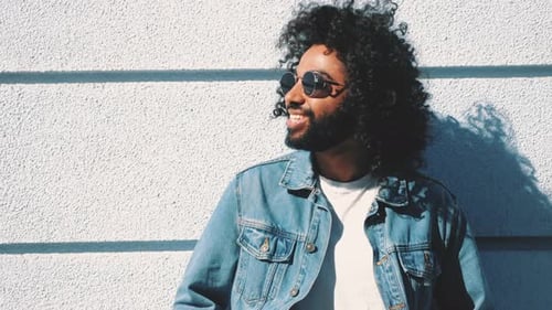 Cool Man with Curly Hair Leaning Against Wall