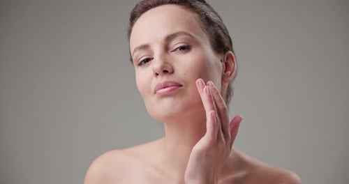 Woman Gently Touching Face in Beauty Studio